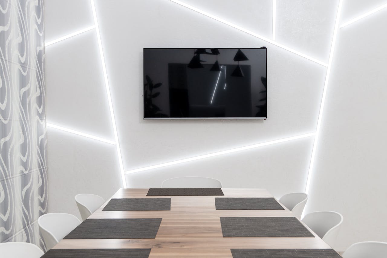 pexels-photo-7005477 Minimalist conference room with LED-lit geometric wall and sleek table.